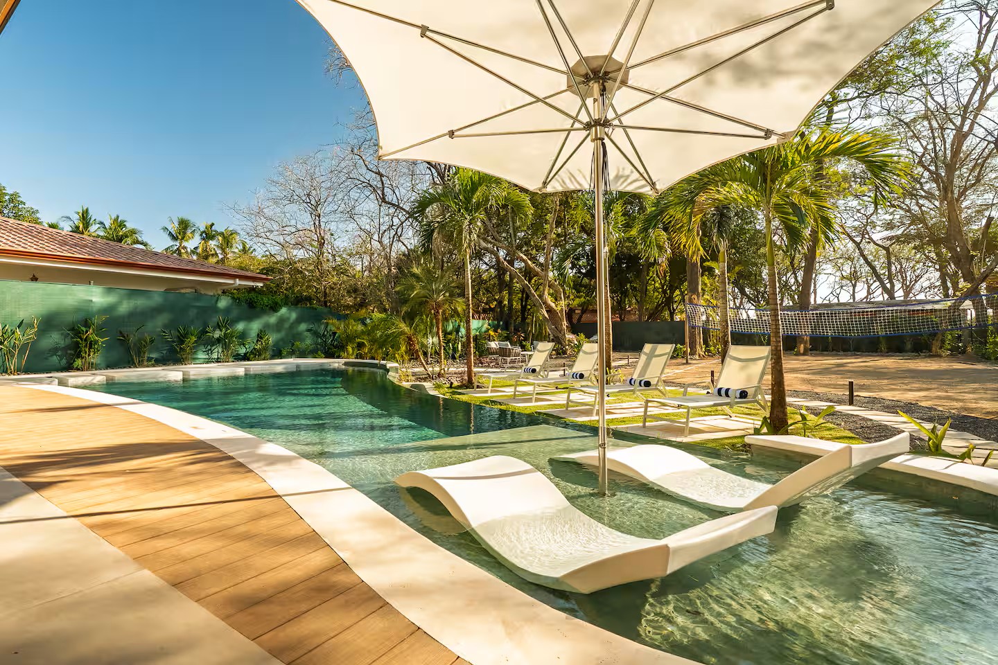 In-water loungers in the curved pool, with new palms and lawn beyond, Villa Viva landscape, Playa Grande